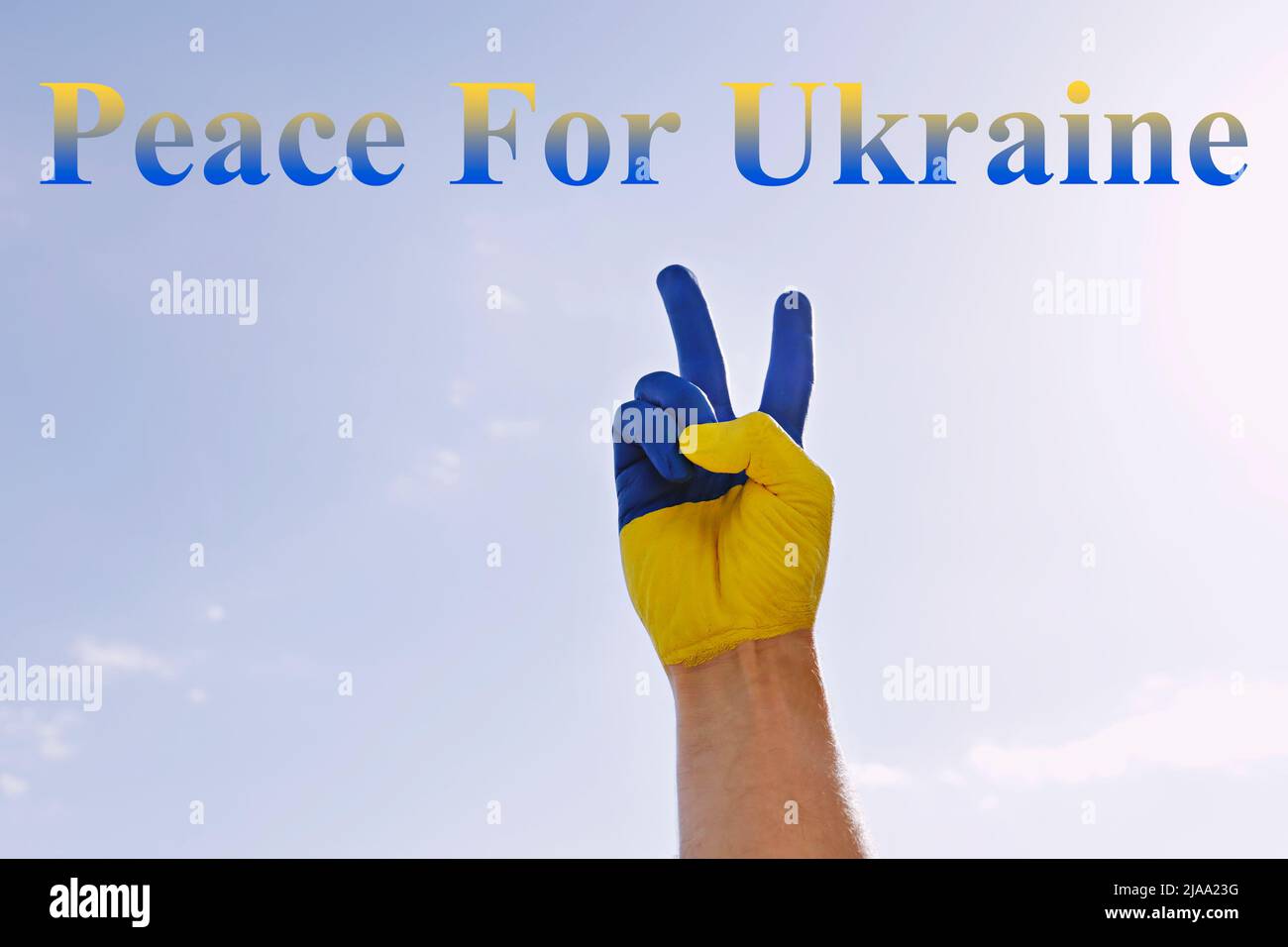 Texte « Peace for Ukraine » écrit sur fond bleu ciel. Main de l'homme peinte en couleurs du drapeau national ukrainien montrant un geste de paix comme signe de Banque D'Images