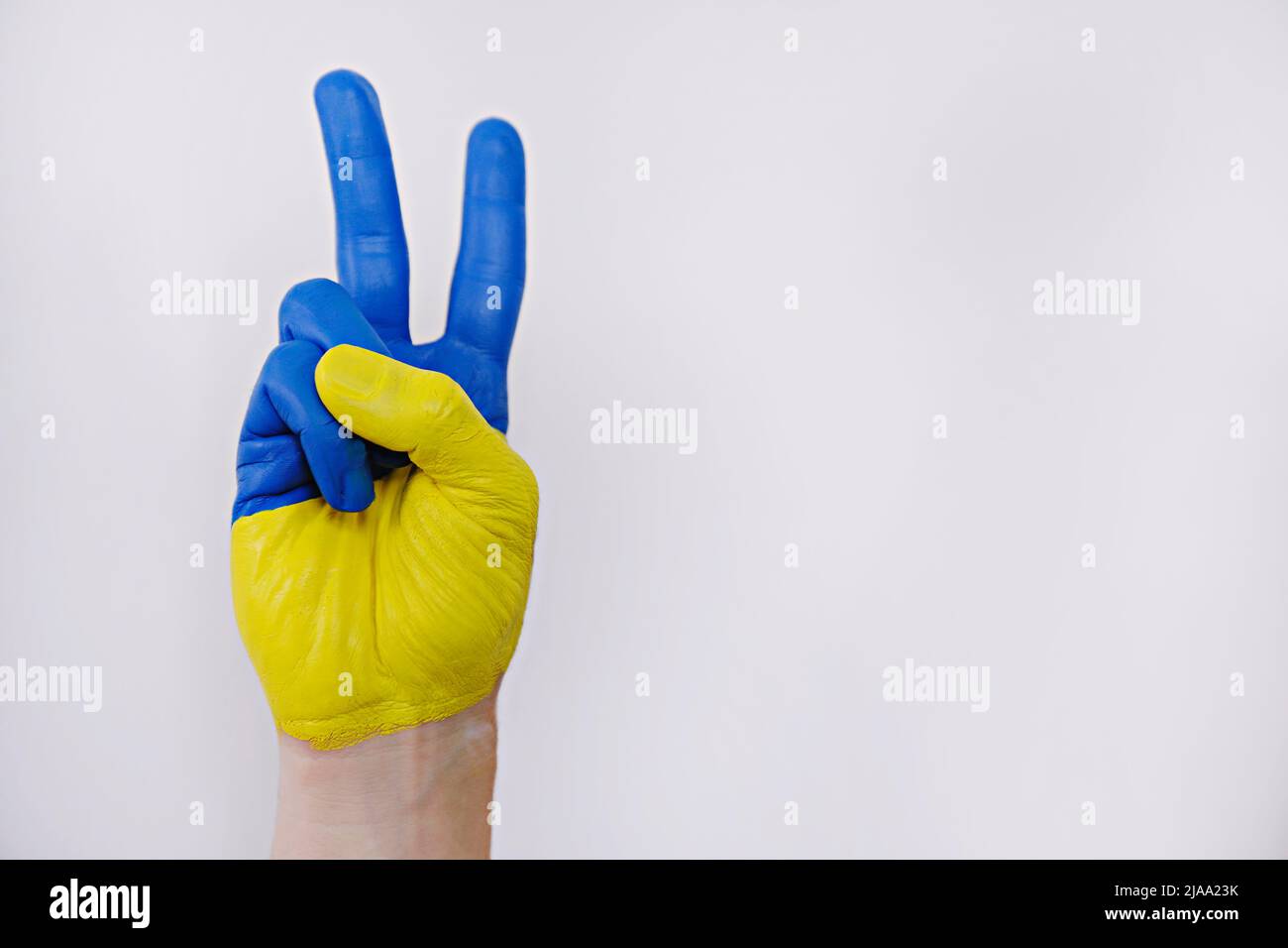 Main de l'homme peinte dans les couleurs du drapeau ukrainien montrant un geste de paix symbolique sur fond blanc isolé. Copier l'espace, gros plan. Banque D'Images