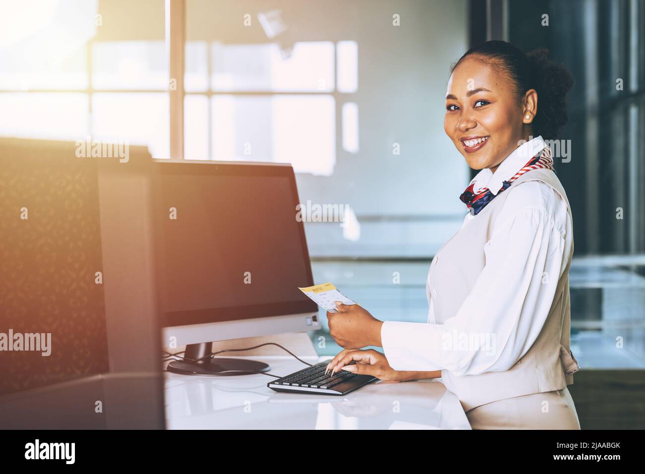 accueil de l'aéroport par une hôtesse au sol à l'enregistrement de la compagnie aérienne personnel au comptoir le sourire heureux Banque D'Images