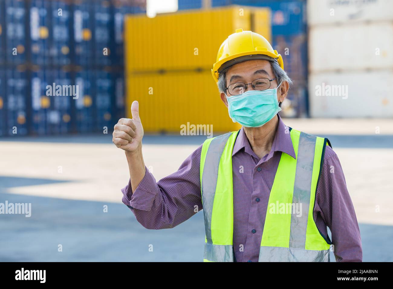 travailleur aîné en bonne santé avec masque de pouce vers le haut. Asiatique chinois vieil homme ingénieur du personnel contremaître bonne santé. Banque D'Images