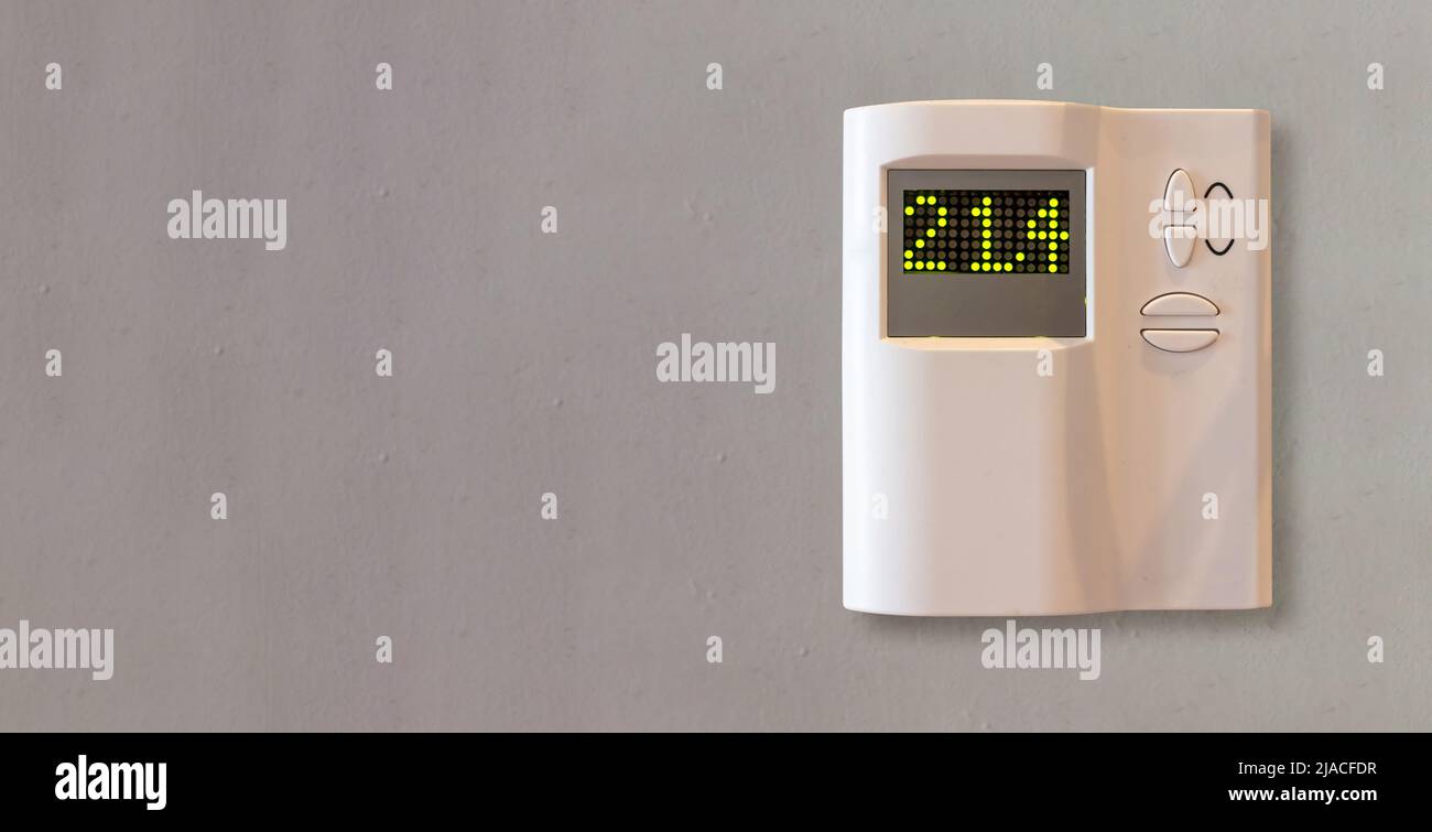 Thermostat numérique sur fond gris de mur vide. Appareil de contrôle de la température du chauffage domestique vue de face rapprochée, espace de copie. Banque D'Images