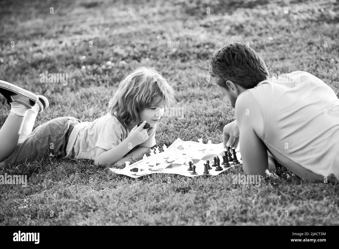 Une famille heureuse à l'extérieur. Père et fils jouant aux échecs dans le jardin de printemps. Banque D'Images