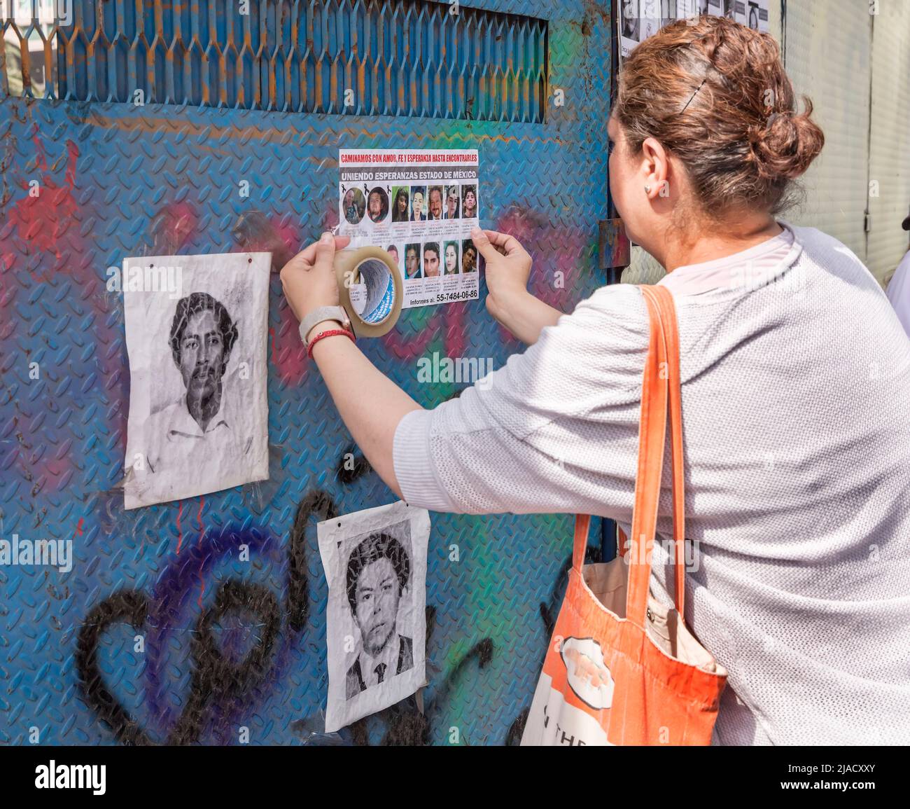 Une femme pose une affiche des personnes disparues sur un mur à Mexico, au Mexique Banque D'Images