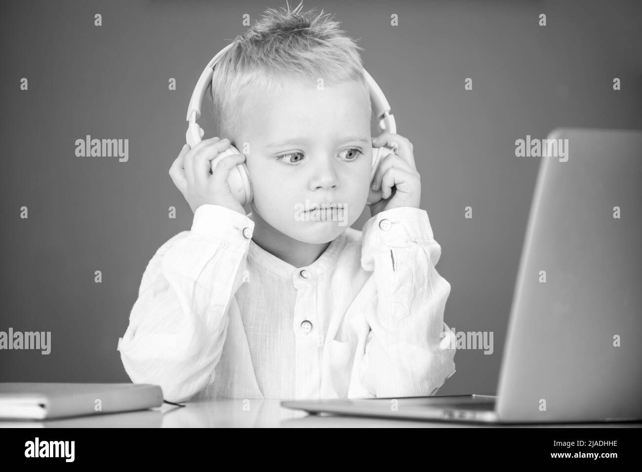 Petit garçon dans le casque regarder la leçon vidéo sur l'ordinateur à l'école, enfant dans les écouteurs ont la leçon en ligne, en utilisant l'ordinateur portable.Formation informatique. Banque D'Images