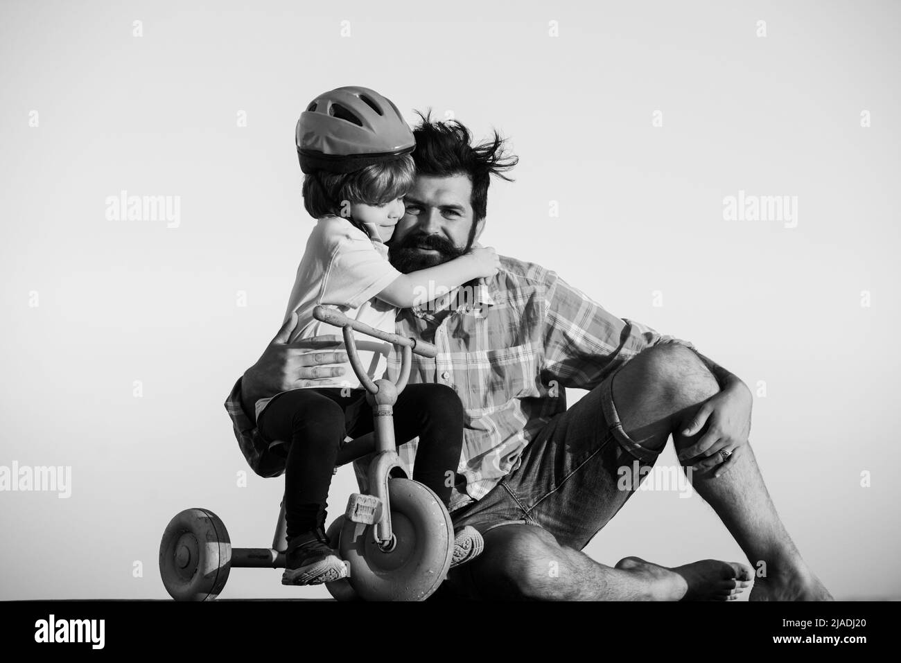 Fils embrassant le père. Papa aide l'enfant à faire du vélo. Banque D'Images