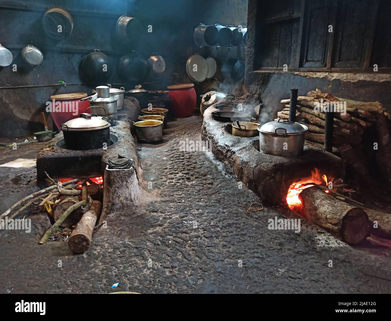 Cuisine de campagne dans le centre de Java, Indonésie avec un poêle allongé qui peut être utilisé pour plusieurs pots, avec des bûches de bois de chauffage Banque D'Images