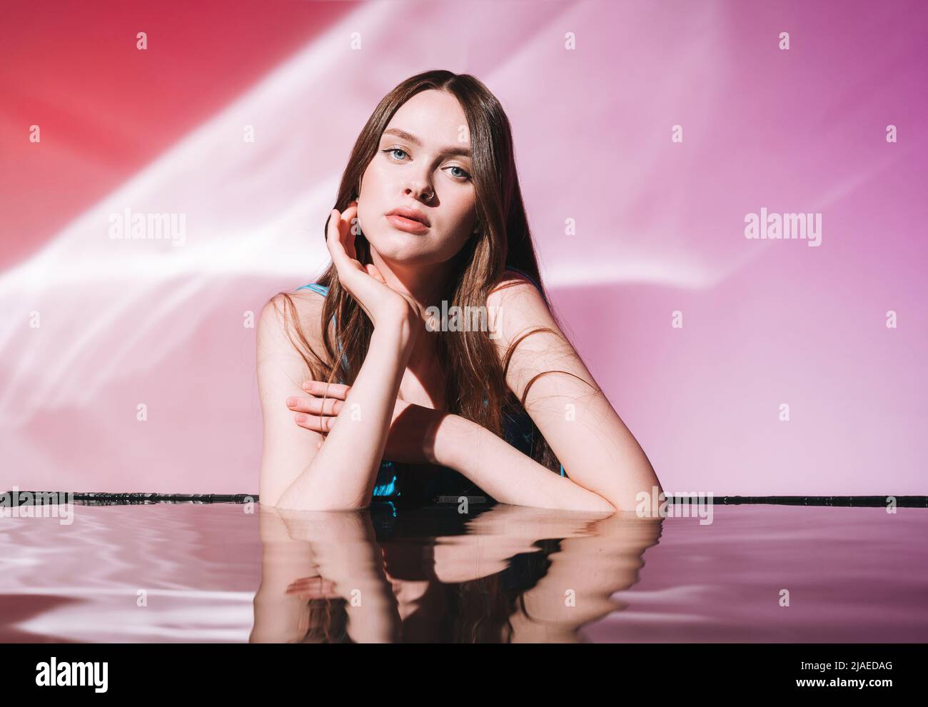 Portrait de beauté avec l'eau de la jeune femme modèle de mode avec des cheveux longs sombres et sains sur fond rose Banque D'Images
