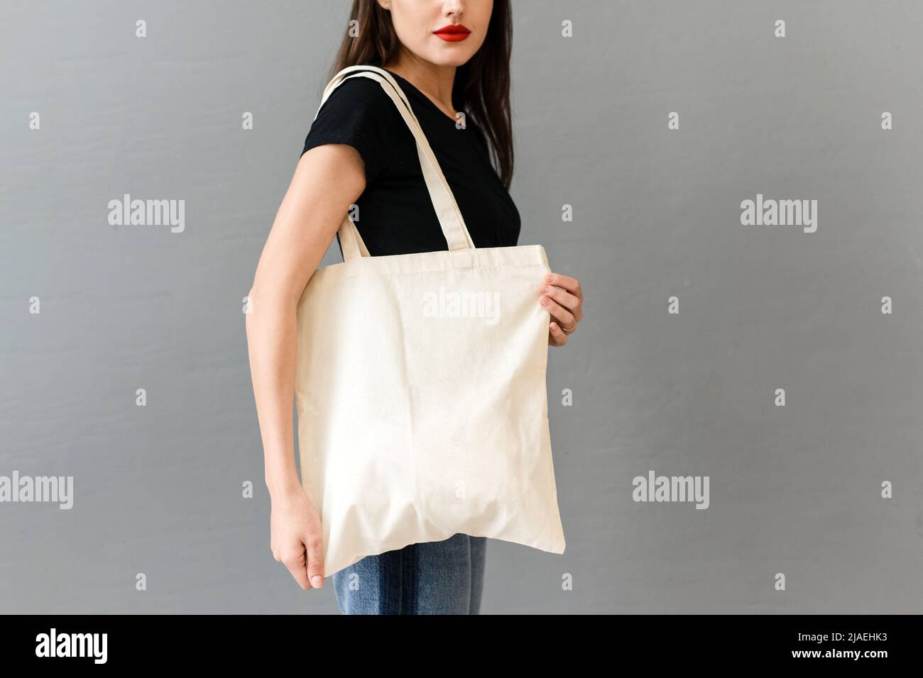 Femme avec sac écologique sur fond gris. Maquette pour un sac fourre-tout design. Banque D'Images