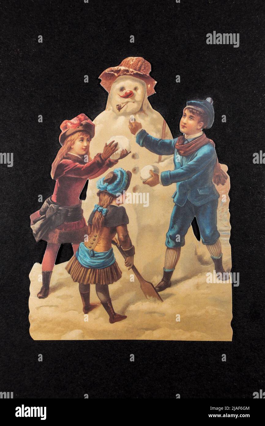 Une carte de Noël traditionnelle (réplique) montrant trois enfants faisant un bonhomme de neige , un morceau de réplique de souvenirs liés à Noël. Banque D'Images