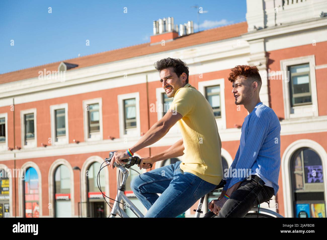 Jeune gay couple de sexe masculin avec bracelets gay Pride profiter d'une balade à vélo en plein air. concept lgbt Banque D'Images