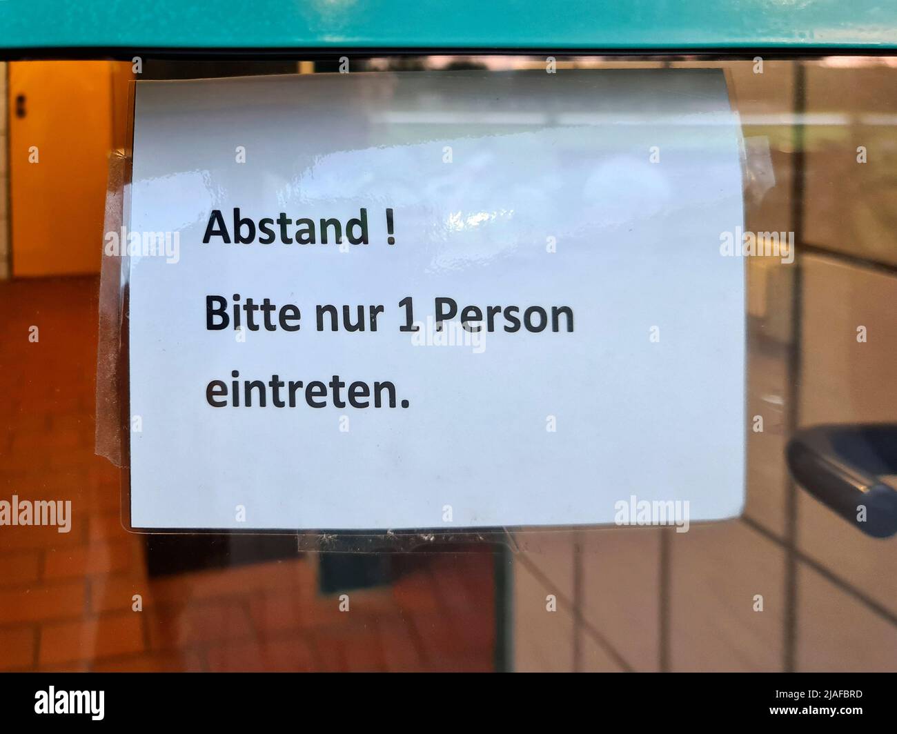 Remarque sur une porte vitrée « Distance! Veuillez entrer seulement 1 personnes, Allemagne Banque D'Images