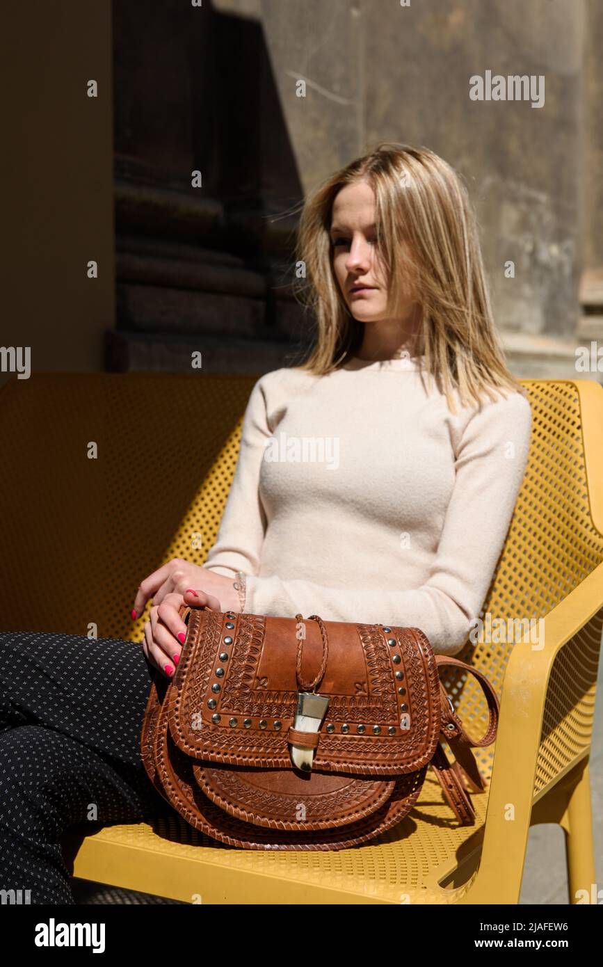 femme avec petit sac en cuir marron avec un motif sculpté. attention sélective Banque D'Images