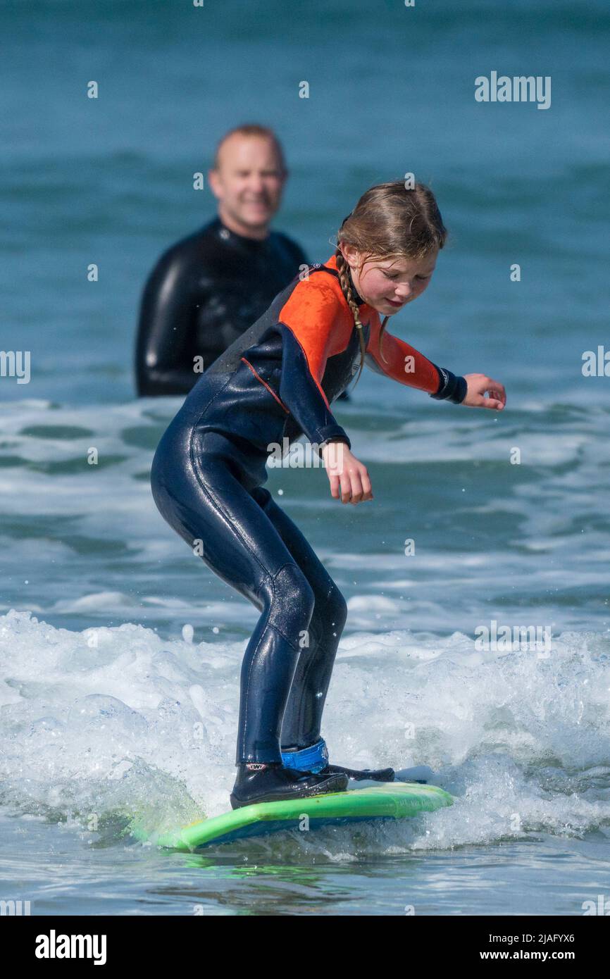 Georgina Fletcher, âgée de 10 ans, de St Austell, apprend à surfer tandis que son fier père regarde à Fistral Beach à Newquay pendant un temps exceptionnellement chaud Banque D'Images