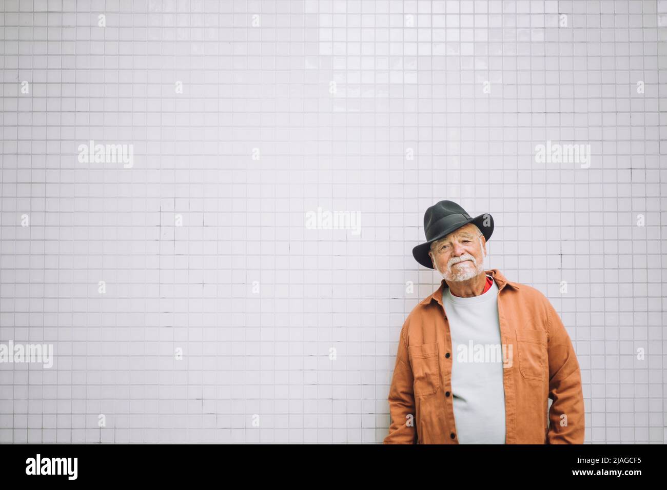 Portrait d'un homme âgé portant un chapeau debout devant un mur blanc Banque D'Images