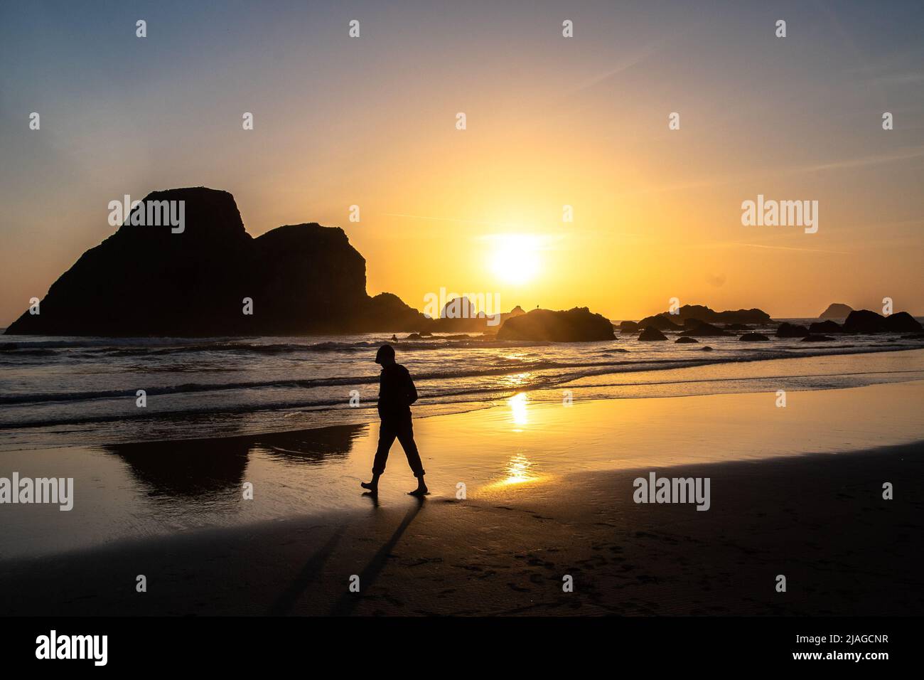 Un enfant marchant le long d'une plage à Arcata ca, comme le soleil silhouettes contre lui. Banque D'Images