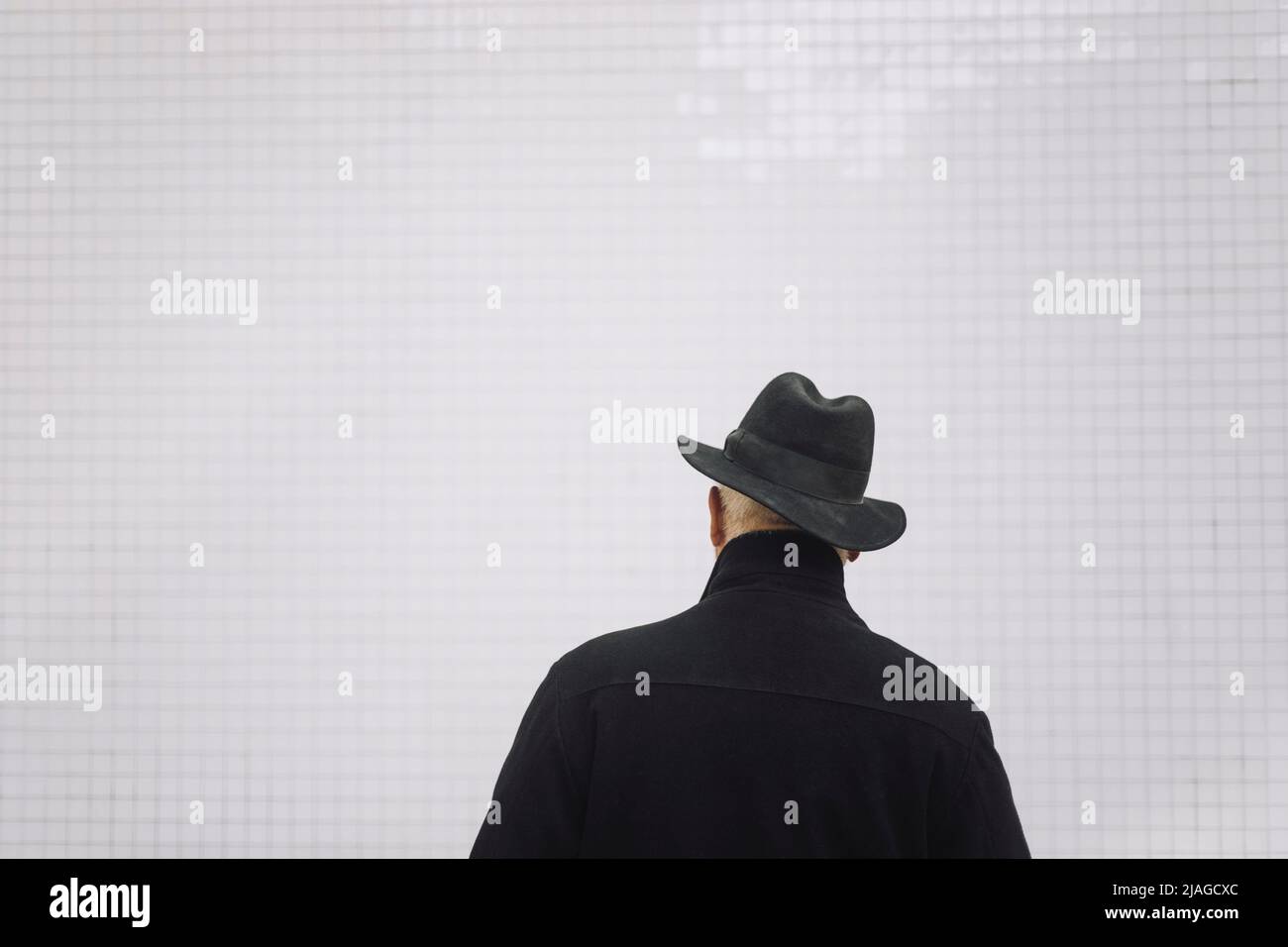 Vue arrière de l'homme âgé portant un chapeau devant le mur blanc Banque D'Images