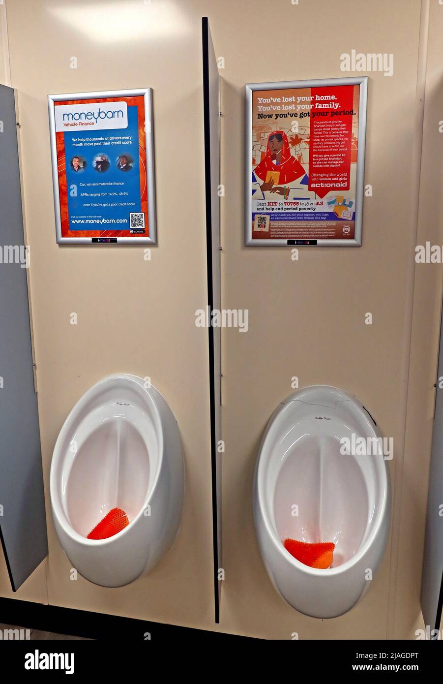 Publicités et promotions typiques dans les toilettes de la station de service d'autoroute, au-dessus des urinoirs - Moneygrange véhicule voiture van finance, ActionAid période pauvreté Banque D'Images