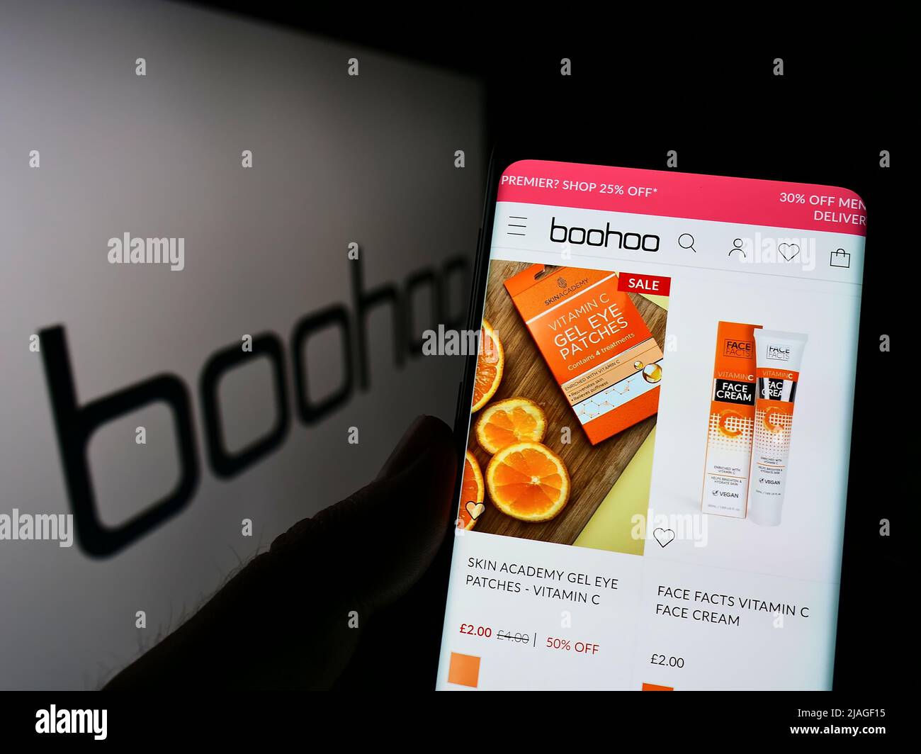 Personne tenant un smartphone avec la page Web de la société de mode britannique Boohoo Group plc à l'écran devant le logo. Concentrez-vous sur le centre de l'écran du téléphone. Banque D'Images