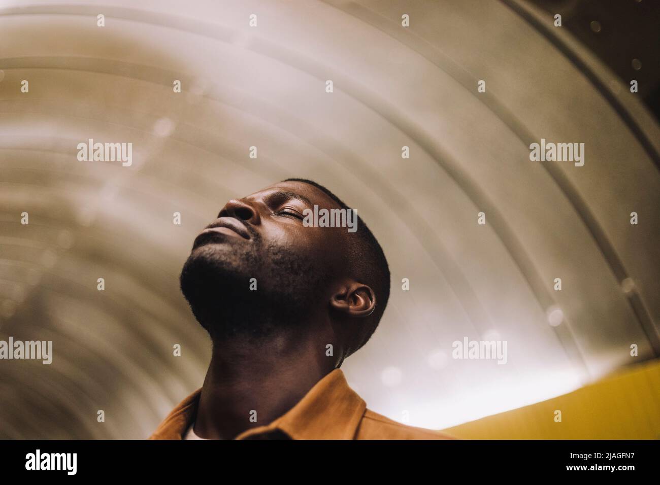 Jeune homme avec les yeux fermés dans le tunnel de métro Banque D'Images