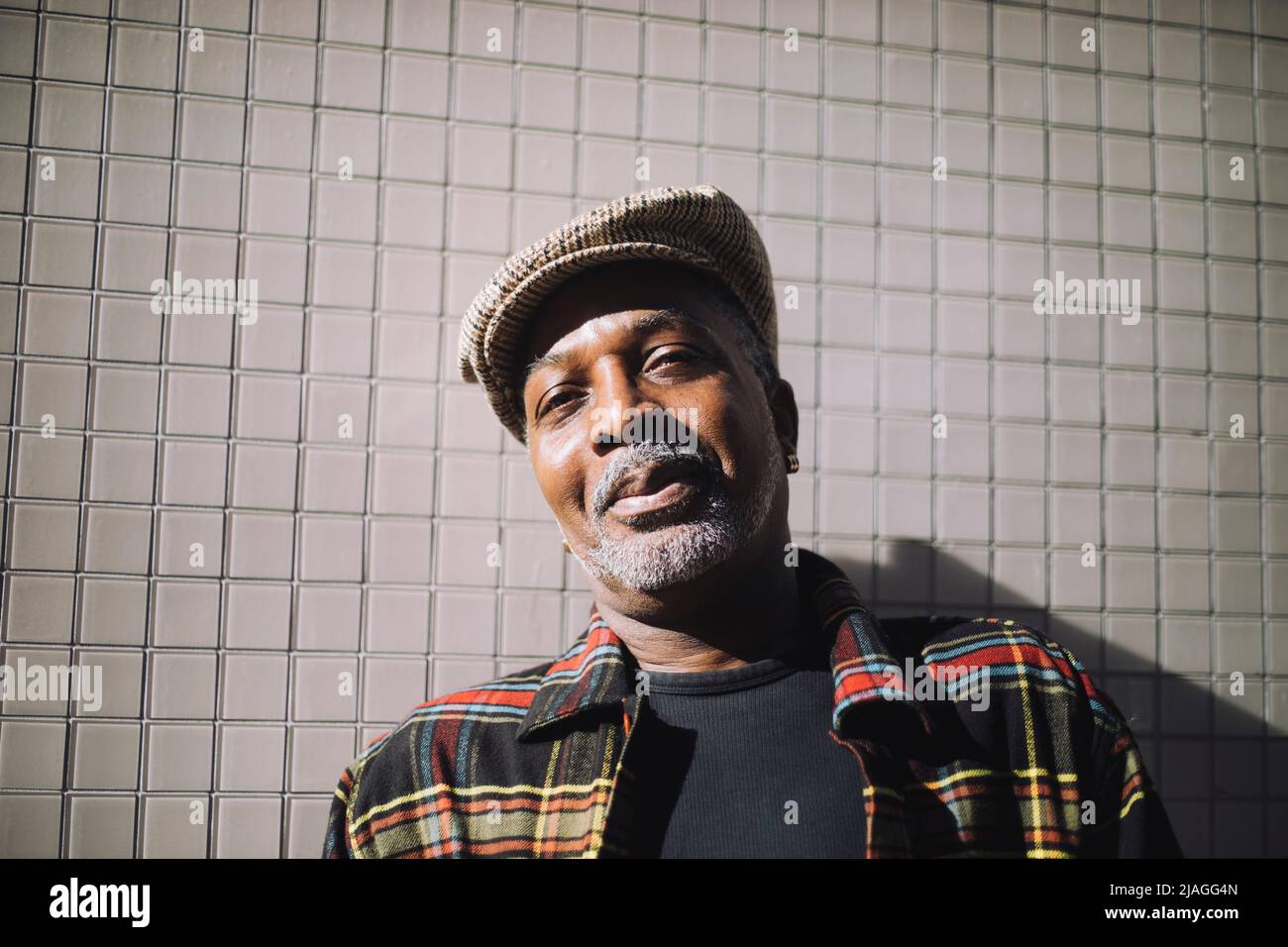 Portrait d'un homme mûr souriant portant une casquette plate contre le mur Banque D'Images