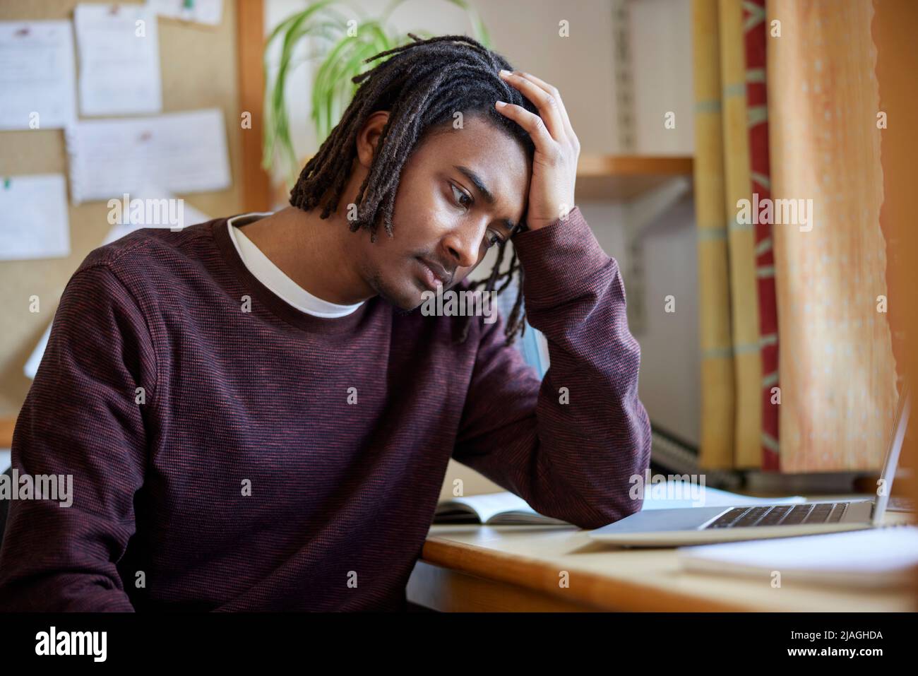 Un étudiant de l'université ou du collège avec un manque de santé mentale étudie avec un ordinateur portable au bureau dans la chambre Banque D'Images