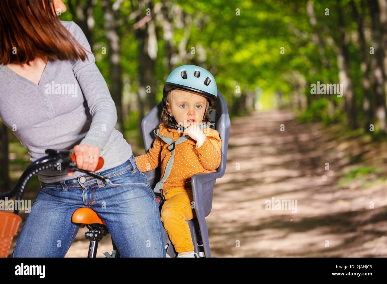 Une jeune fille s'assoit dans un siège à vélo avec sa mère dans le parc Banque D'Images