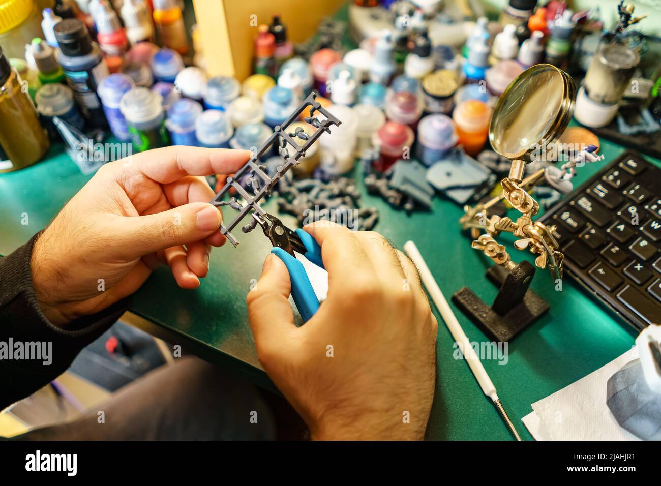 Homme coupant de petits morceaux de jeux de miniatures pour peindre à la main. Banque D'Images