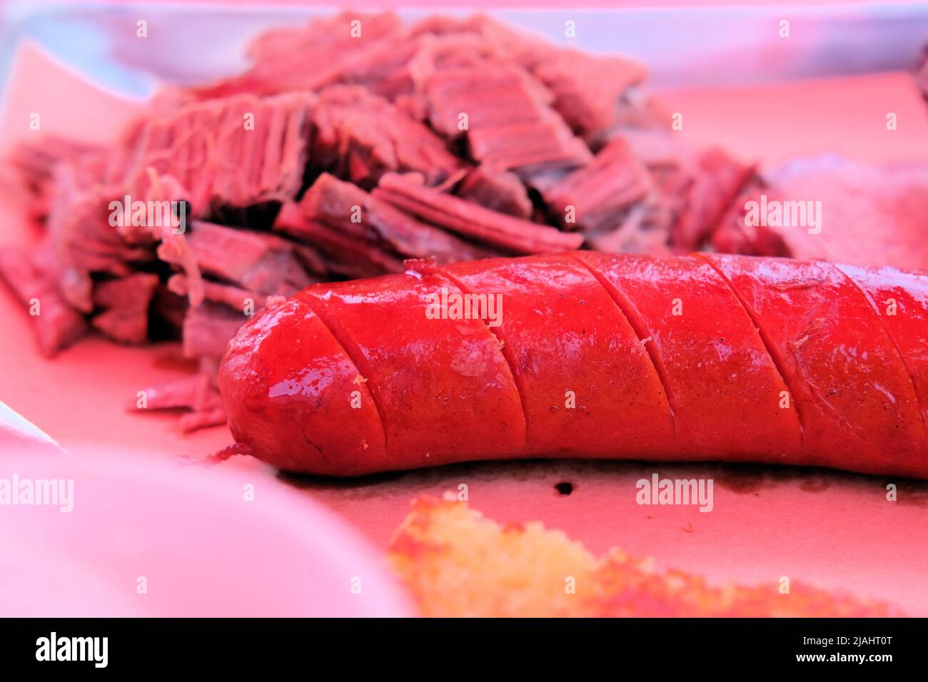 Saucisse de porc fumée avec fentes pour couper facilement et poitrine de bœuf tirée en arrière-plan ; barbecue américain prêt à manger ; barbecue de style sudiste. Banque D'Images