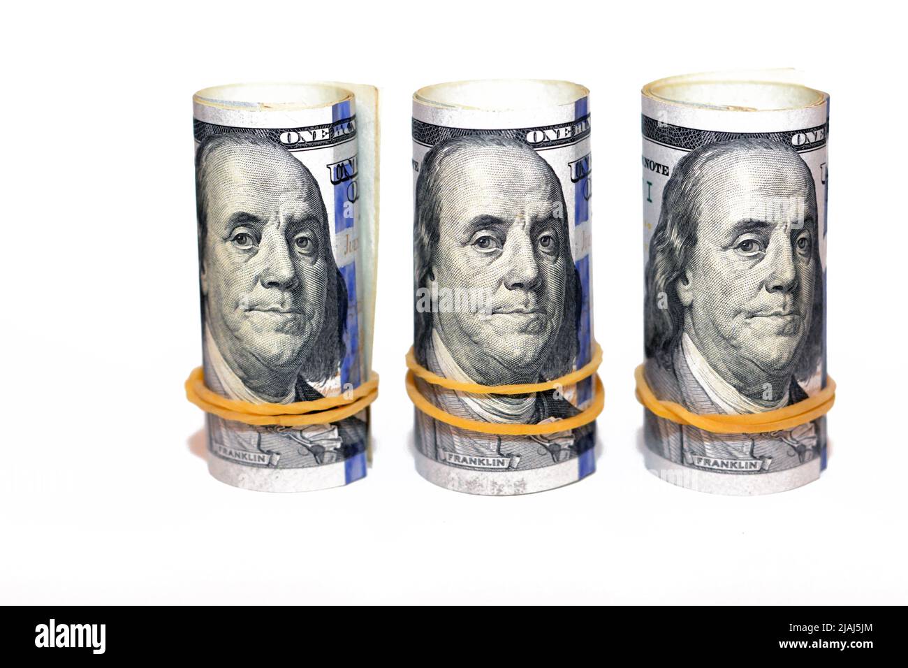 Paquets de rouleaux d'argent de dollars isolés sur fond blanc, pile de cent dollars US cash billets roulés avec des bandes de caoutchouc avec l'esprit Banque D'Images