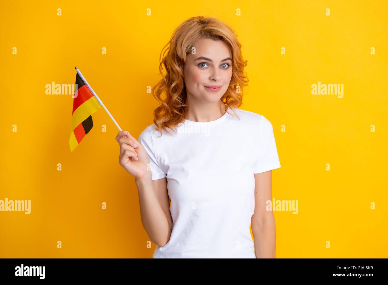 Portrait d'une étudiante positive portant le drapeau allemand. Isolé sur fond jaune. Bonne fille tenant le drapeau de l'Allemagne, l'immigration et les voyages Banque D'Images