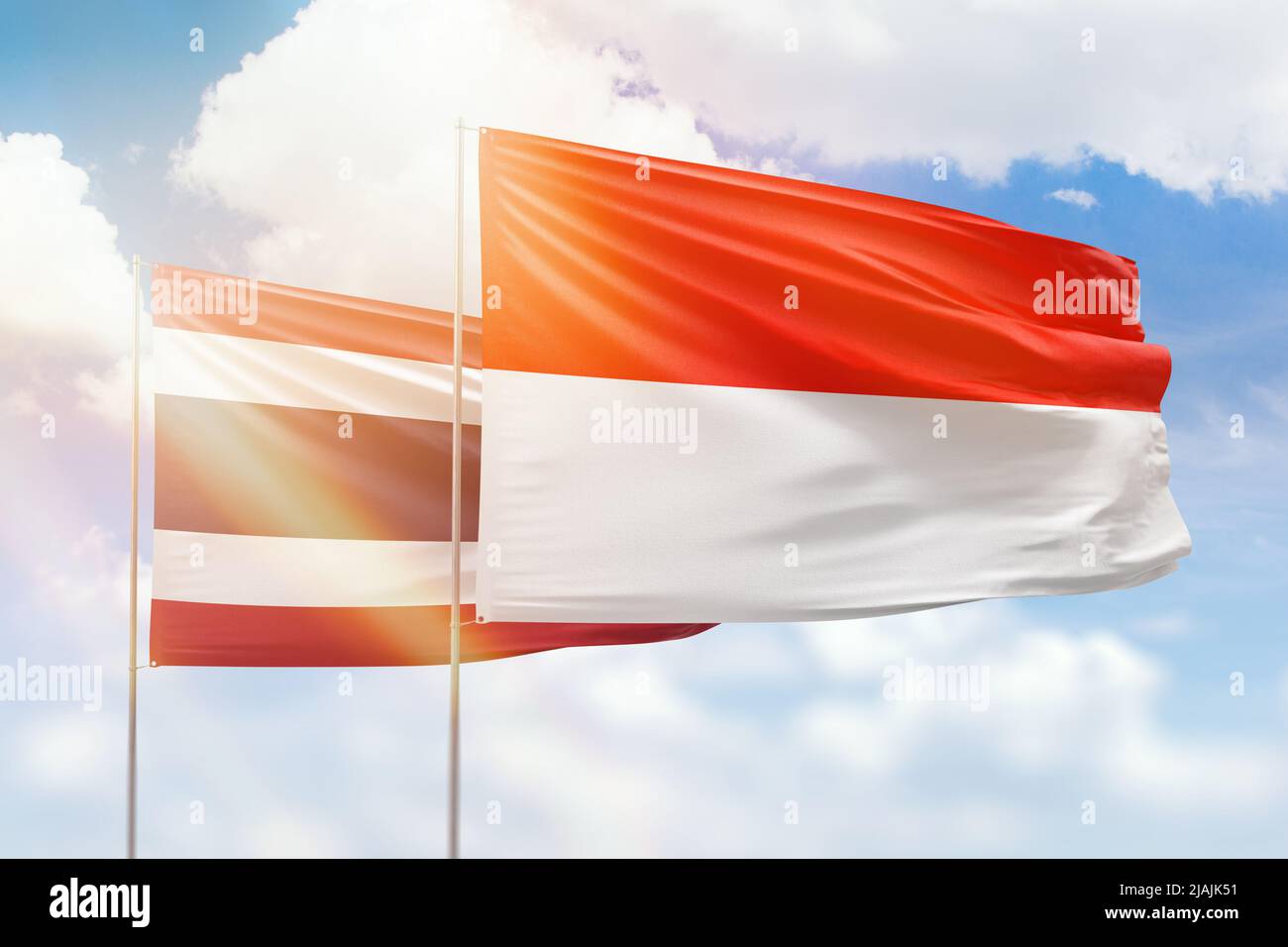 Ciel bleu ensoleillé et drapeaux de l'indonésie et de la thaïlande Banque D'Images