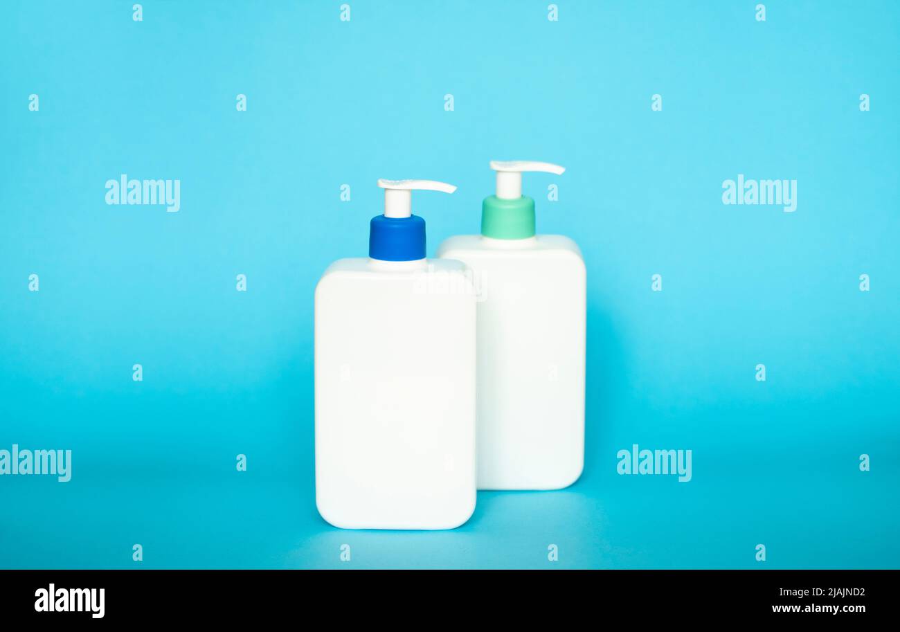 Flacons de shampooing ou de après-shampooing avec pompe à distributeur sur fond bleu. Banque D'Images