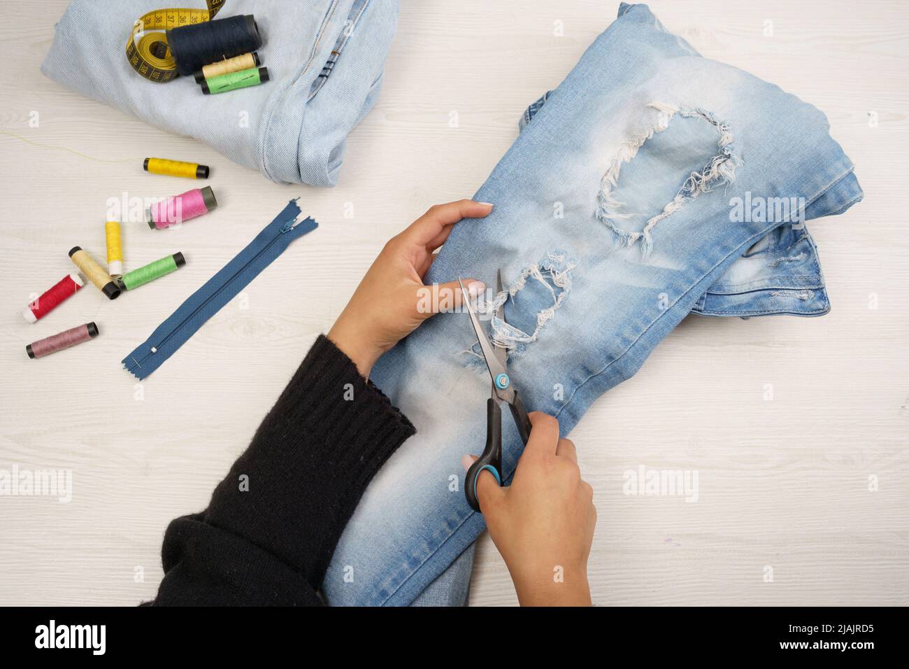 détails de la coupe des mains de vêtements pour jeunes, utilisation de ciseaux dans les textiles, travail de couturier, texture et objets en studio Banque D'Images
