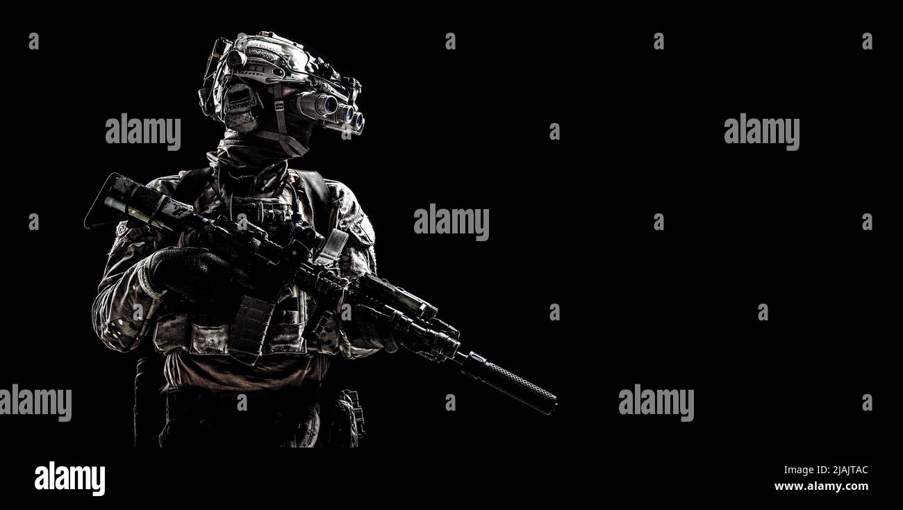 Soldat des forces spéciales debout dans l'obscurité équipé de lunettes de vision nocturne et d'un fusil d'assaut. Banque D'Images