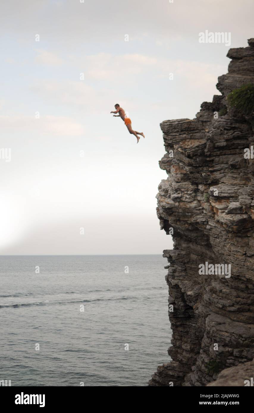 Un homme saute d'une falaise élevée dans la mer Banque D'Images