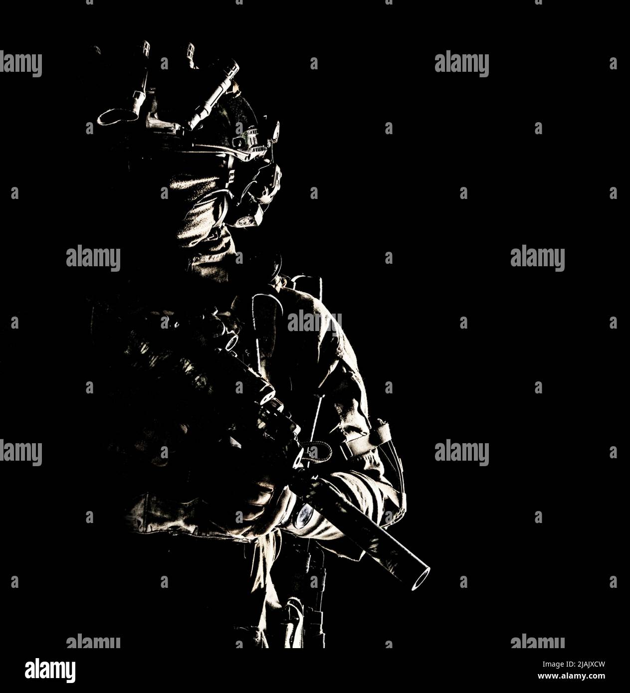 Soldat des forces spéciales équipé d'un dispositif de vision nocturne et d'un canon de sous-machine avec silencieux. Portrait en studio sur fond noir. Banque D'Images