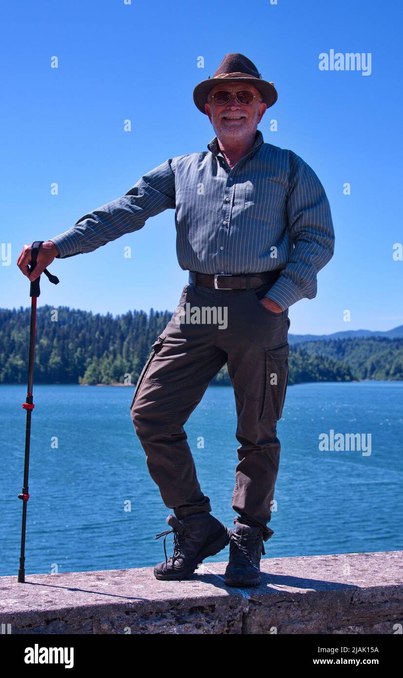 Homme senior en vêtements de chasse debout au bord du lac Banque D'Images