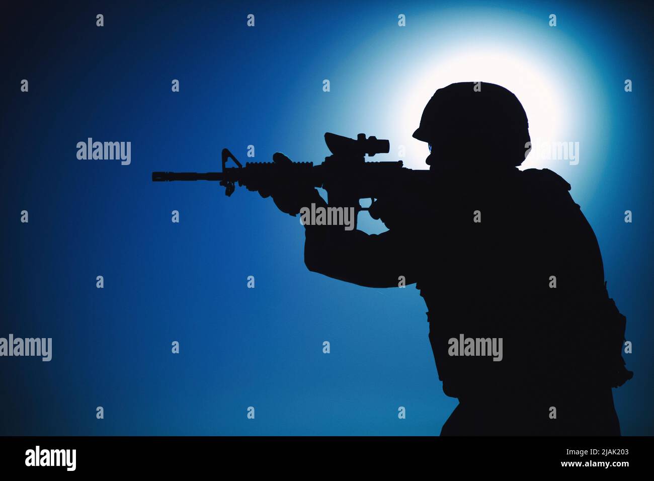 Silhouette d'un soldat visant une carabine d'assaut avec collimateur de vue la nuit. Banque D'Images