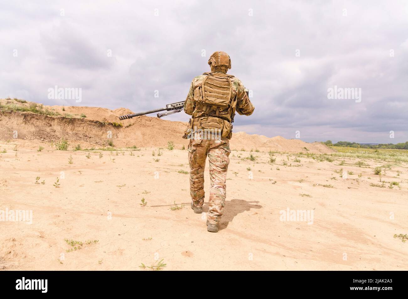 Soldat des forces spéciales en camouflage à la carabine, marchant dans le désert Banque D'Images