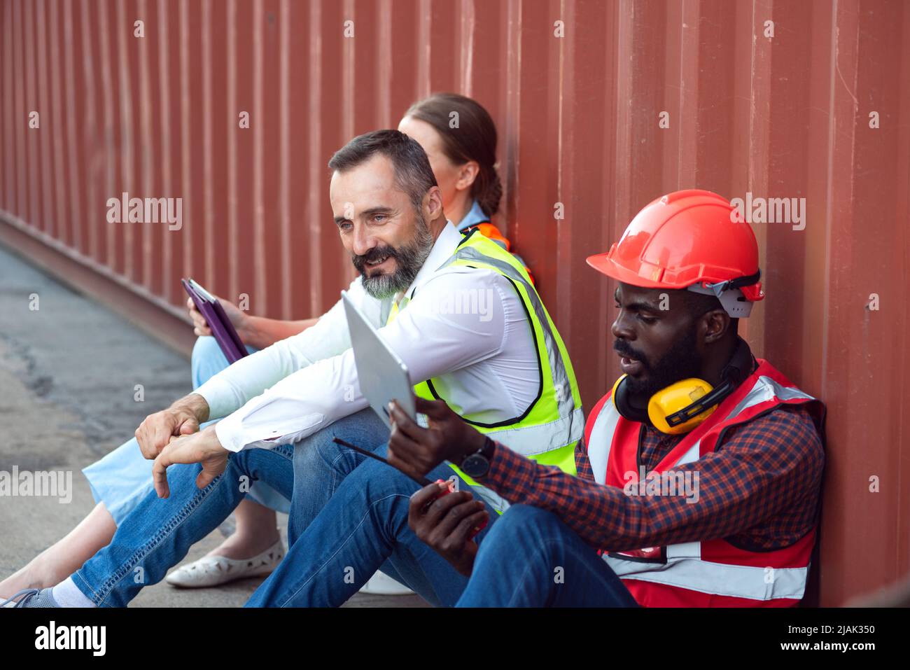 Deux responsables et un ingénieur s'assoient pour discuter de leur travail d'expédition au client. Distribution stockage commerce fret port. Banque D'Images