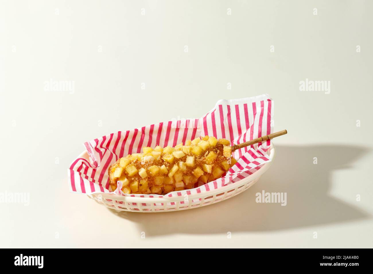Délicieux croquant Coréen Chunky Potato Corn Dogs avec pâte et pommes de terre frites. Isolé sur fond crème avec espace de copie pour le texte Banque D'Images