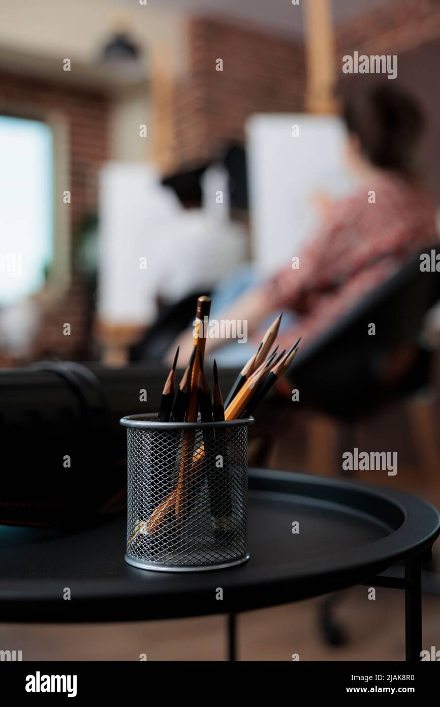 Gros plan des crayons graphiques debout sur une table dans une école d'art pédagogique. En arrière-plan, diverses équipes dessinant des croquis de vase sur toile travaillant à la technique d'esquisse. Résolutions du nouvel an Banque D'Images