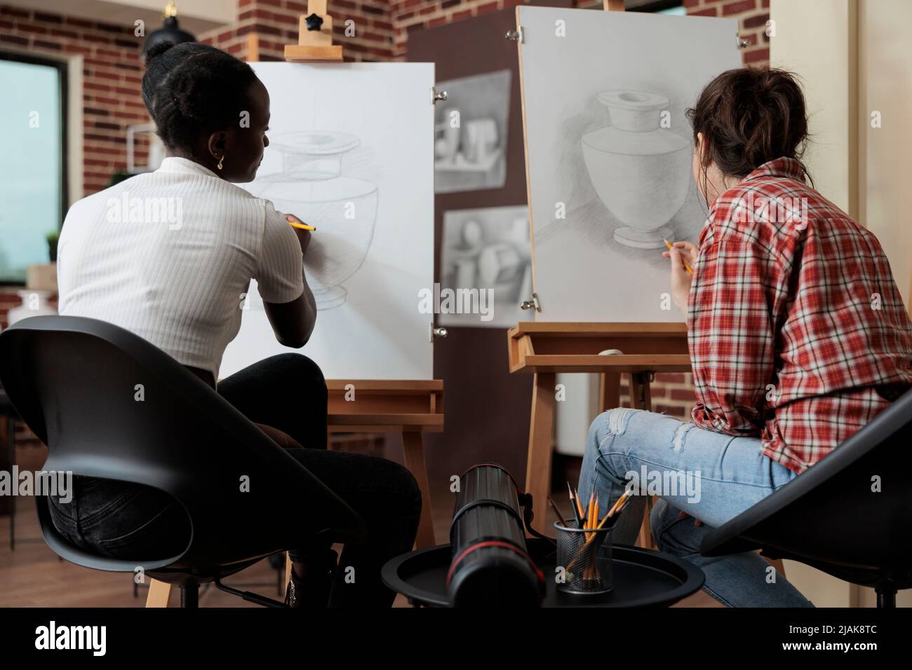 Équipe diversifiée travaillant à l'art projet dessin vase esquisse sur toile blanche en utilisant la technique d'illustration. Les étudiantes qui suivent la leçon d'esquisse apprennent de nouvelles compétences artistiques pour la croissance personnelle Banque D'Images