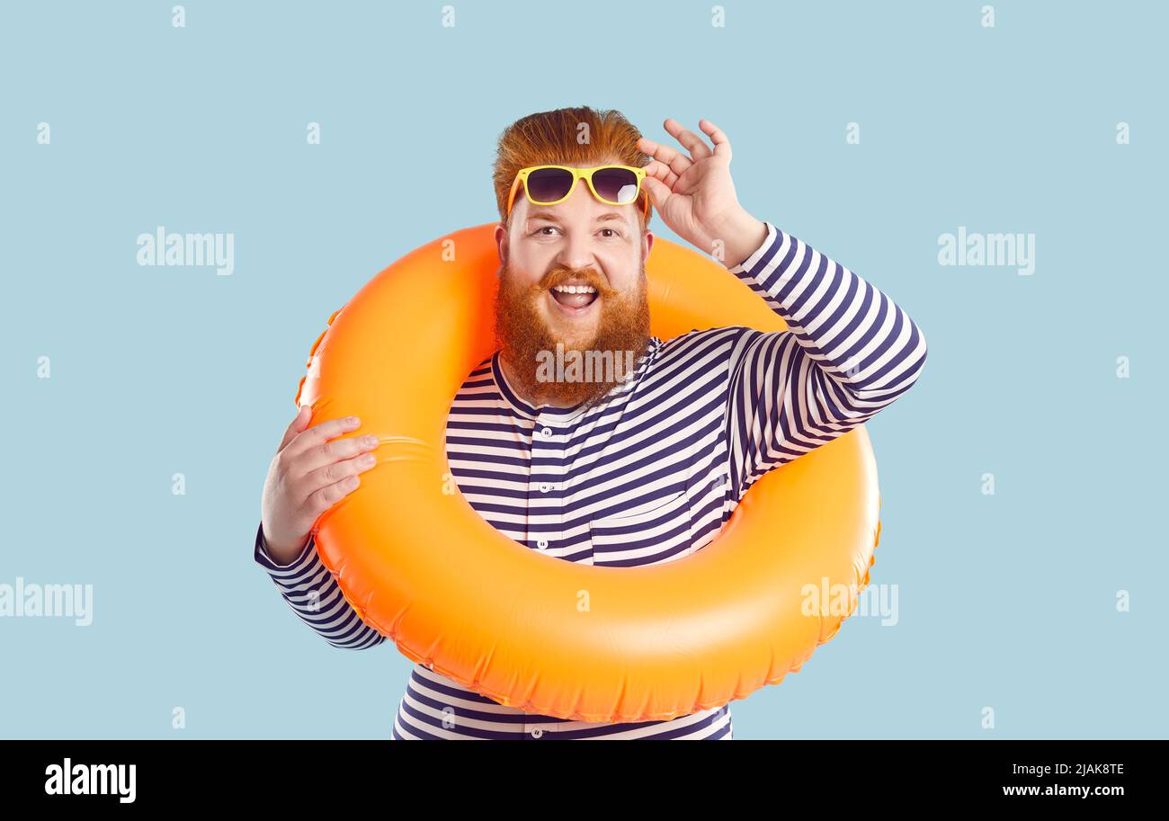 Drôle de gros homme avec la bouée de sauvetage autour de son cou, la taille et des lunettes de soleil isolé sur fond bleu clair. Banque D'Images