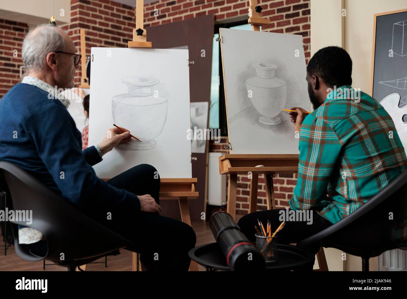 Étudiants multiethniques esquissant un modèle de vase sur toile à l'aide d'un crayon graphique travaillant à la technique de dessin pendant les cours d'art en studio de créativité. Équipe diversifiée développant de nouvelles compétences artistiques Banque D'Images