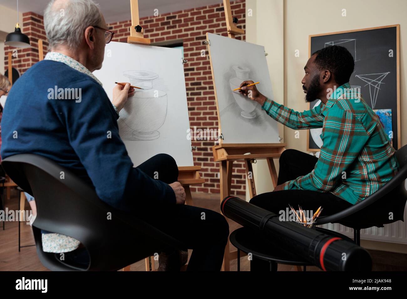 Modèle de vase de dessin étudiant afro-américain sur toile blanche utilisant un crayon graphique travaillant à la technique d'esquisse pendant la classe d'art dans le studio de créativité. Équipe diversifiée développant de nouvelles compétences artistiques Banque D'Images