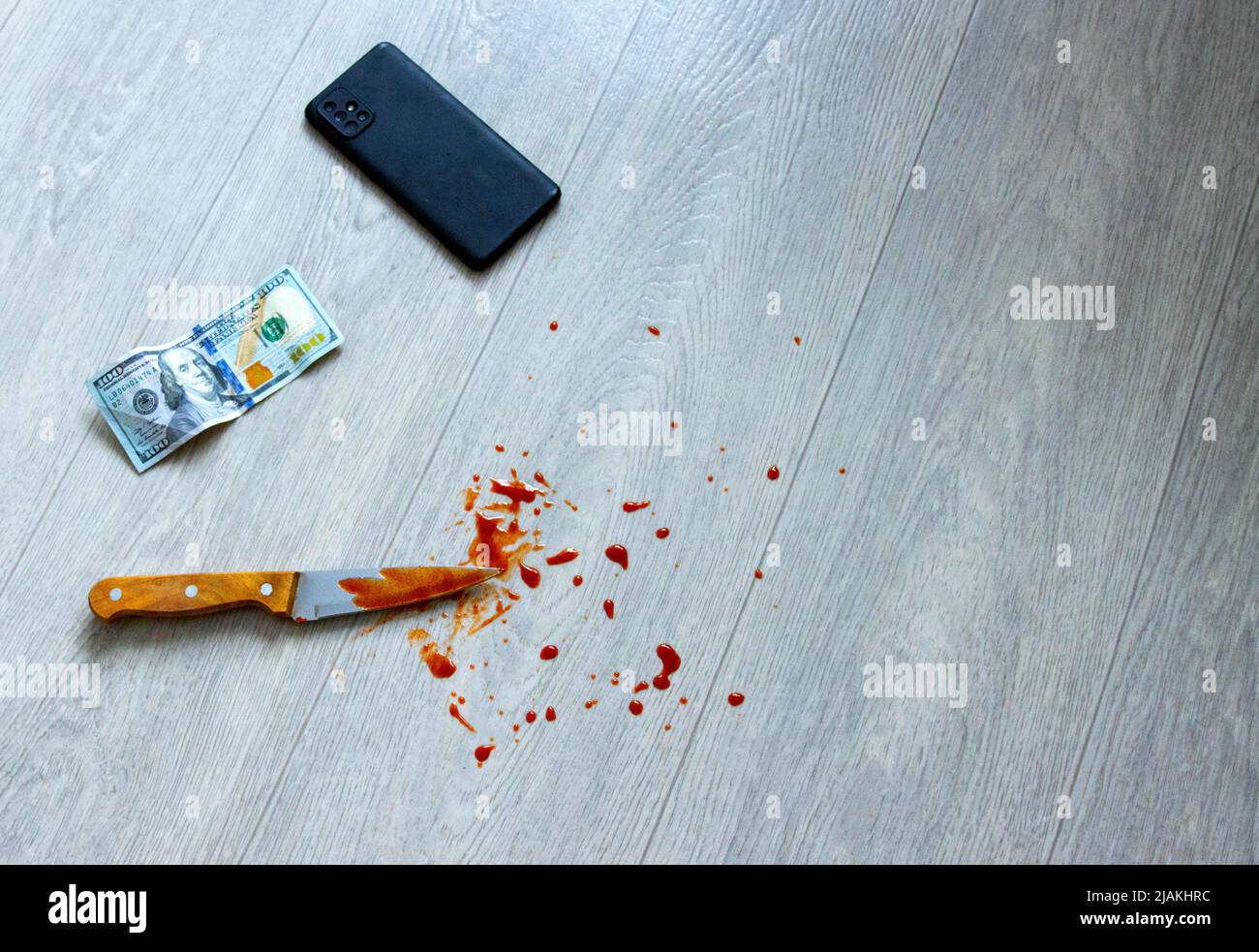 Un smartphone, un couteau sanglant et des dollars d'argent se trouvent sur le sol. Le concept de vol avec un vol. Banque D'Images