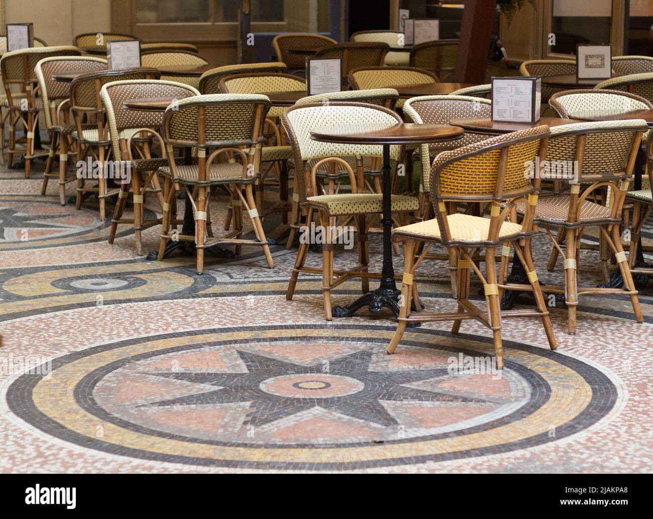 Places et tables en plein air dans un café français du centre de Paris. Tables et chaises avec un beau sol en mosaïque. Personne Banque D'Images