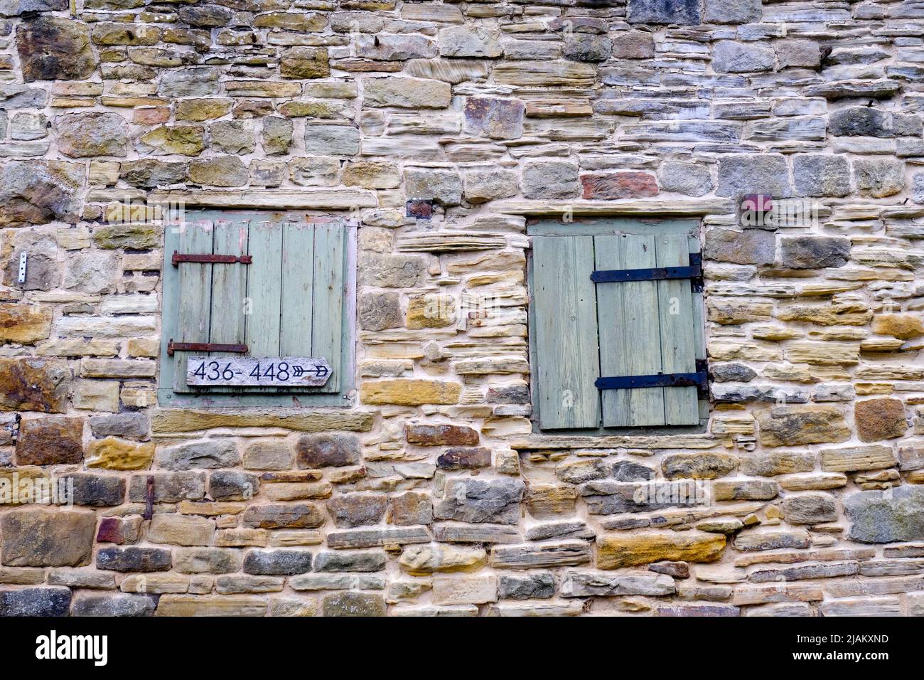 Un vieux mur en pierre récemment repointée contenant deux portes à charnières peintes en bois. Banque D'Images