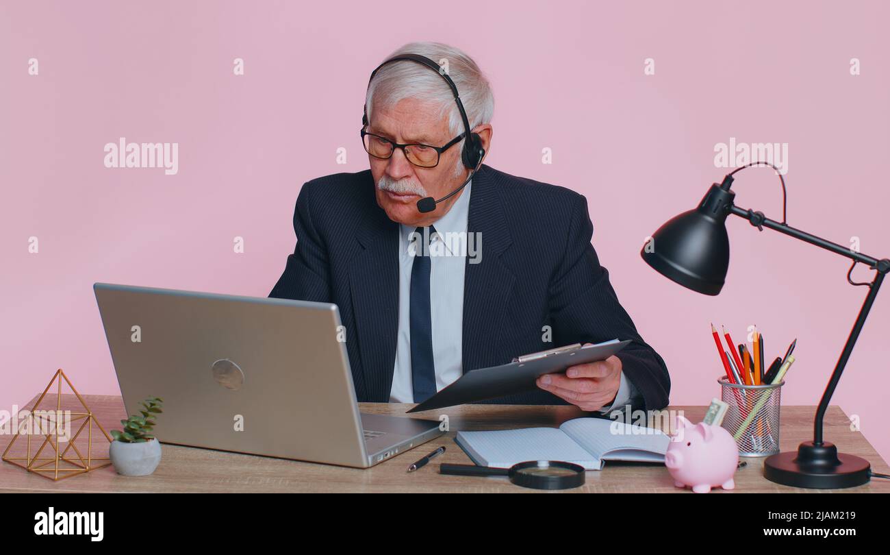 Un homme d'affaires expérimenté porte un casque sans fil pour passer des appels vidéo de conférence sur un ordinateur portable. Homme âgé professionnel agent de centre d'appels, opérateur ayant à distance webcam chat entretien de travail sur ordinateur dans le bureau Banque D'Images